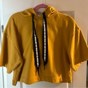 Mustard colored, short sleeve, hooded sweatshirt.